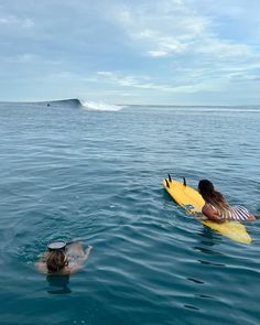 two people in the water with surfboards and one person swimming on their stomachs