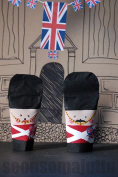 two pairs of black slippers sitting on top of a table in front of a british flag banner