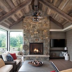 a living room with a stone fireplace and ceiling fan