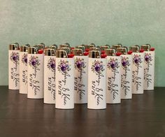 six white flasks with purple flowers and writing on them