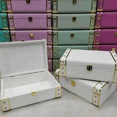 two white boxes sitting next to each other in front of many colored chests with gold handles