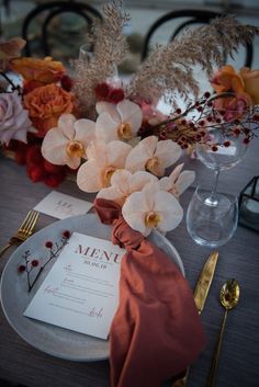 an elegant table setting with flowers and menu