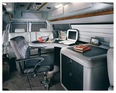 the interior of an airplane with desk, computer and office chair in front of it