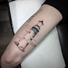 a small lighthouse tattoo on the arm