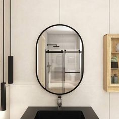 a black sink sitting under a mirror in a bathroom next to a shelf with vases on it