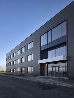 an empty street in front of a building with many windows on the side of it