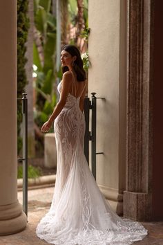 a woman in a wedding dress is standing by some pillars and looking off into the distance