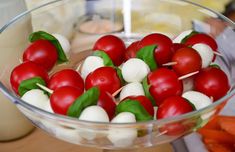 tomatoes, mozzarella and spinach on skewers in a glass bowl