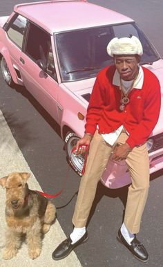 a man sitting on top of a pink car next to a brown dog with a leash