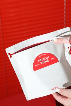 a person holding a white bag with red writing on it and a pair of scissors sticking out of it