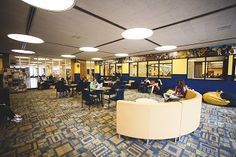 people are sitting at tables and eating in the cafeteria area of an office building,