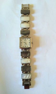 "This heavy silver watch is like wearing a dressy bracelet. The links have gray and white mother of pearl shell set into rectangular hinged pieces.  The face is also mother of pearl.  Back says: Perennial, Japan movement, stainless steel comeback, made in China.  Almost brand new, all it needs is a battery.  Length is 6.5\"." Pearl Watch, Beaded Watches, Pearl Shell, Watch Collection, Curator Style, Vintage Watches, Silver Watch, Vintage Silver, Watch Bands