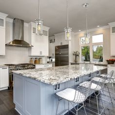 a large kitchen with white cabinets and marble counter tops, along with bar stools