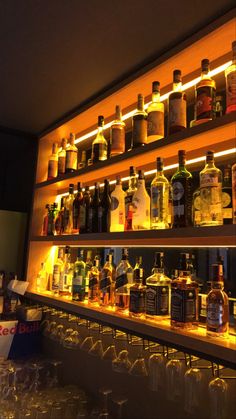 many bottles and glasses are lined up on the bar