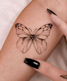 a woman's arm with a black and white butterfly tattoo on the left side