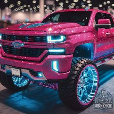 a pink truck with chrome wheels and lights on it's front bumper is parked in a showroom