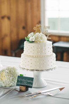 a white wedding cake sitting on top of a table next to a knife and fork