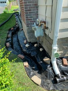 a drain in the ground next to a house with pipes running from it and water coming out