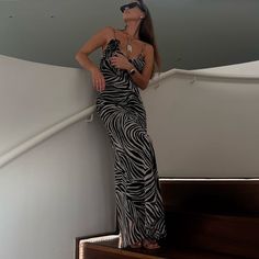 a woman in a zebra print dress standing on the stairs with her hands on her hips