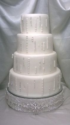 a three tiered white wedding cake sitting on top of a silver tablecloth covered table