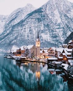 an old town is surrounded by snow covered mountains in the distance, with a lake and mountain range in the foreground