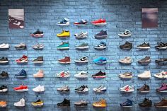 there are many pairs of shoes hanging on the brick wall in front of each other