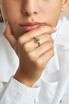 a woman wearing a white shirt is holding her hand to her chin and looking at the camera