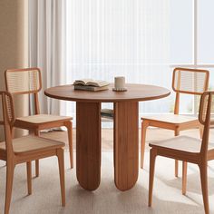 a wooden table with chairs around it in front of a window and a book on top of the table