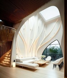 a modern living room with white walls and wood flooring, along with a spiral staircase leading up to the second floor