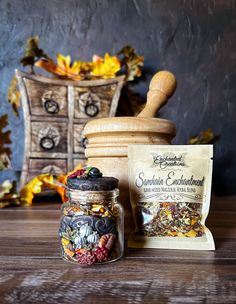 an old fashioned wooden grinder next to a jar filled with dried berries and nuts