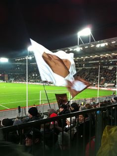 a crowd of people watching a soccer game on a field at night with an american flag in the foreground