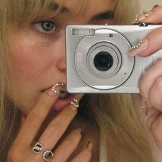 a woman taking a selfie with her camera in front of her face and nails on