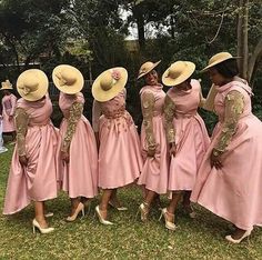 several women in pink dresses and hats are standing on the grass with their hands behind their backs