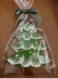 a christmas tree shaped cookie in a plastic bag on a wooden stick with a bow