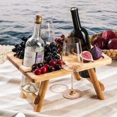 two wine glasses and bottles on a wooden tray with grapes, watermelon, and figurines