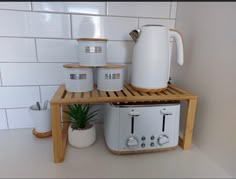 a toaster sitting on top of a wooden shelf next to two white mugs