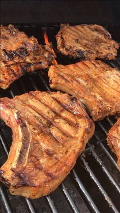 steaks cooking on the grill with tongs sticking out of it's sides