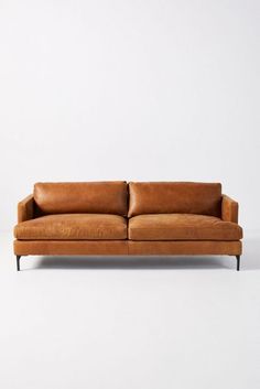 a brown leather couch sitting on top of a white floor