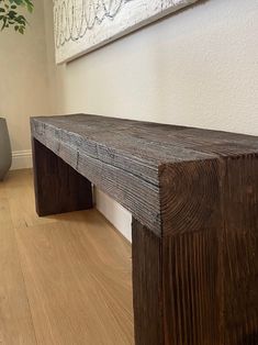 a wooden bench sitting on top of a hard wood floor next to a potted plant