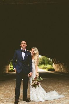 a bride and groom standing in an underpass at their wedding day, posing for the camera