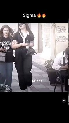 two women are walking down the street in front of a man on his cell phone