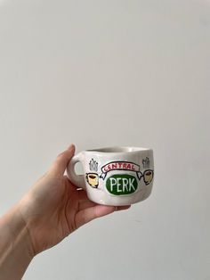 a hand holding a coffee cup with the word perk painted on it