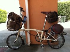 a bicycle parked next to a building with a bag on the front rack and back seat