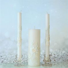 three white candles sitting next to each other in front of a blue and white background