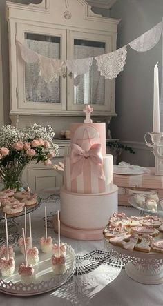 a table topped with cakes and cupcakes covered in pink frosted icing