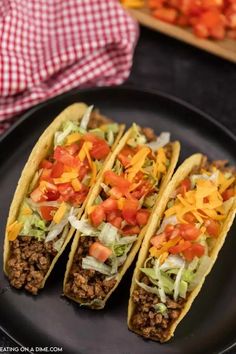 three tacos are sitting on a black plate