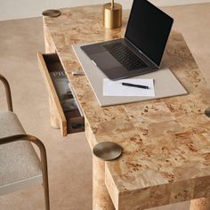 an open laptop computer sitting on top of a wooden desk next to a magazine and pen