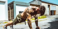 a man doing push ups on his skateboard in front of some buildings and garages