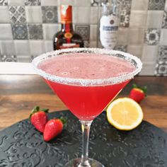 a red drink sitting on top of a table next to strawberries