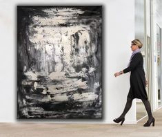 a woman walking past a large black and white painting